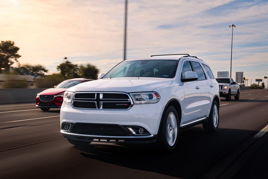 Modern Dodge vehicle with advanced safety sensors and cameras navigating city streets and highway traffic